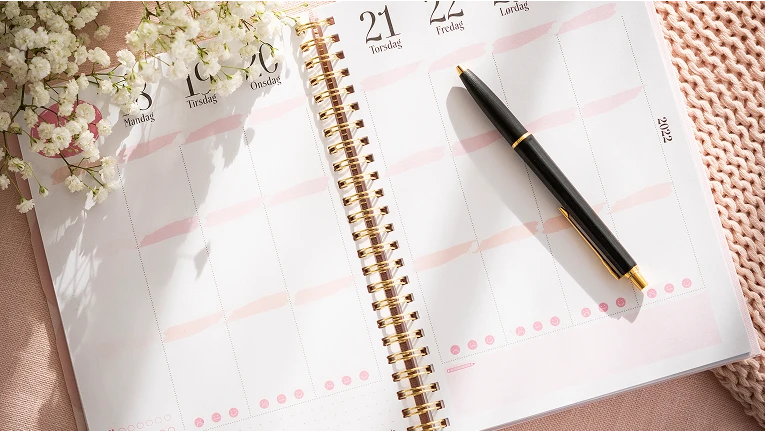 Kalender som ligger på et bord med en blyant oppe på